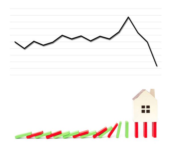 σπίτι στέκεται στην πτώση ντόμινο με ένα γράφημα που υπάγονται σε φόντο ως οικονομική έννοια - Φωτογραφία, εικόνα