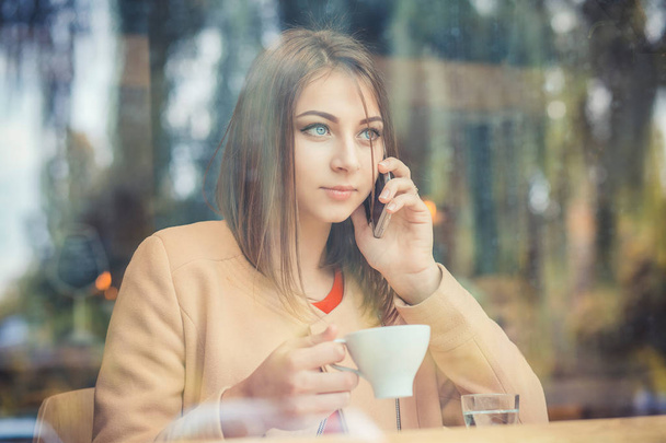 Charming woman talking on mobile phone during rest in coffee sho - 写真・画像
