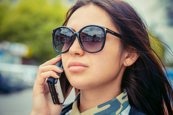 Woman talking at phone. City reflection on sunglasses - Photo, Image