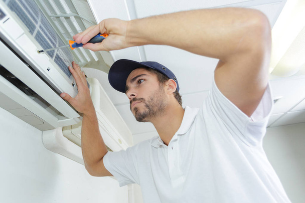 portrait of mid-adult male technician repairing air conditioner - 写真・画像