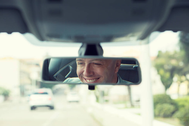 Happy with my car choice. Portrait young man driver reflection in car rear view mirror.  - Foto, Imagem