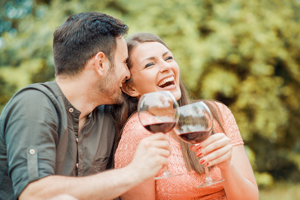 かわいいの若いカップルがピクニックにワインを飲む - 写真・画像