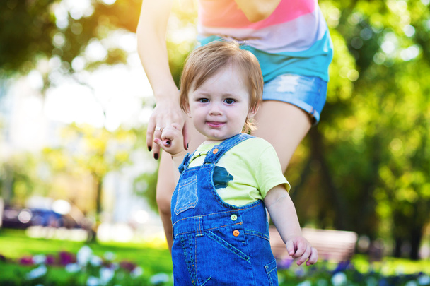 Baby with mom in a greenl summer park - Fotoğraf, Görsel