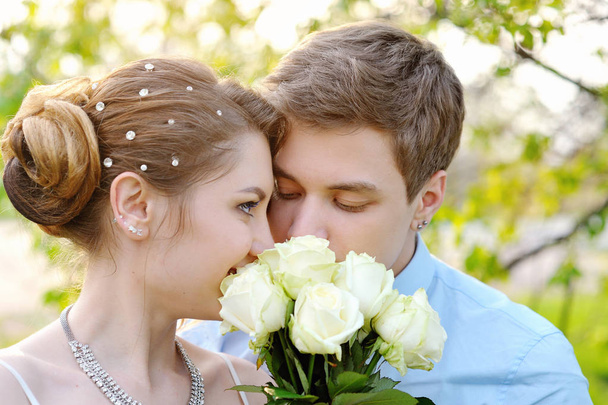 novia y novio en el parque de primavera oliendo una rosa blanca
 - Foto, Imagen