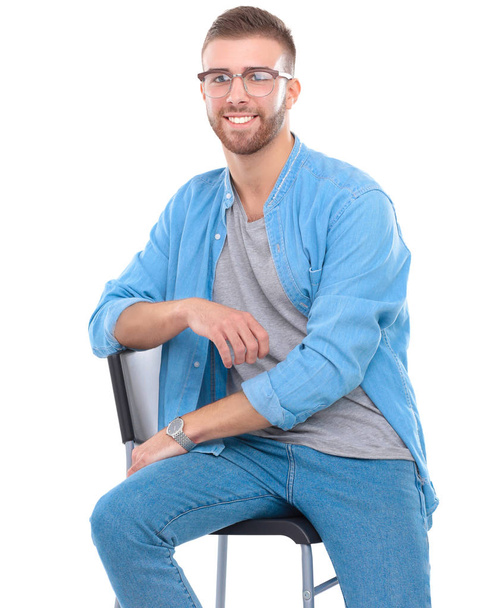 Young man sitting on the chair isolated over white background - Foto, imagen