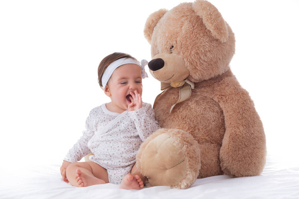 glückliches Baby spielt mit flauschigem Teddybär auf weißem Hintergrund - Foto, Bild