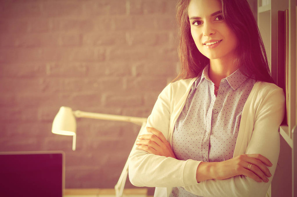 Young woman standing near desk with laptop - Zdjęcie, obraz