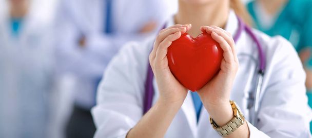 Молодая женщина-врач держит красное сердце
 - Фото, изображение