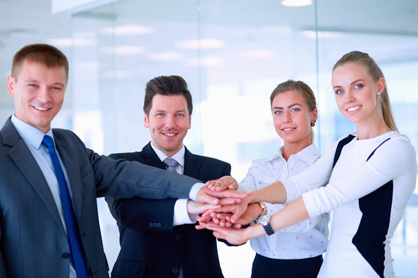 Business team joining hands together standing in office - Foto, Bild
