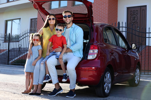 Family with kids sitting in car trunk on sunny day - Фото, изображение