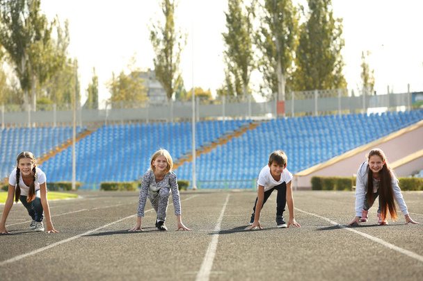 Cheerful children in ready position to run on track - 写真・画像