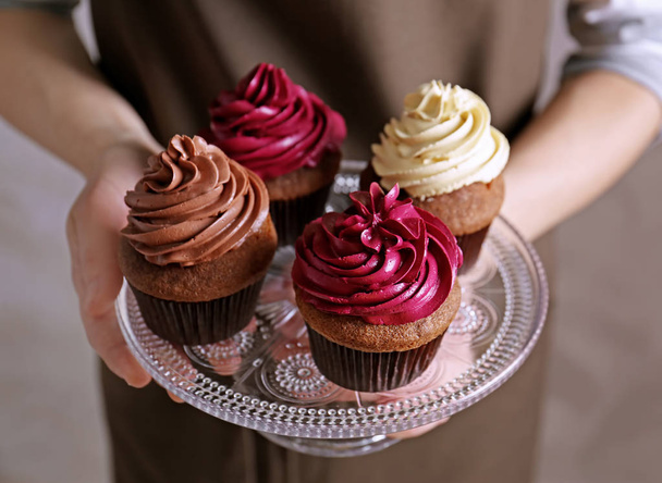 Woman holding tasty chocolate cupcakes - Фото, изображение