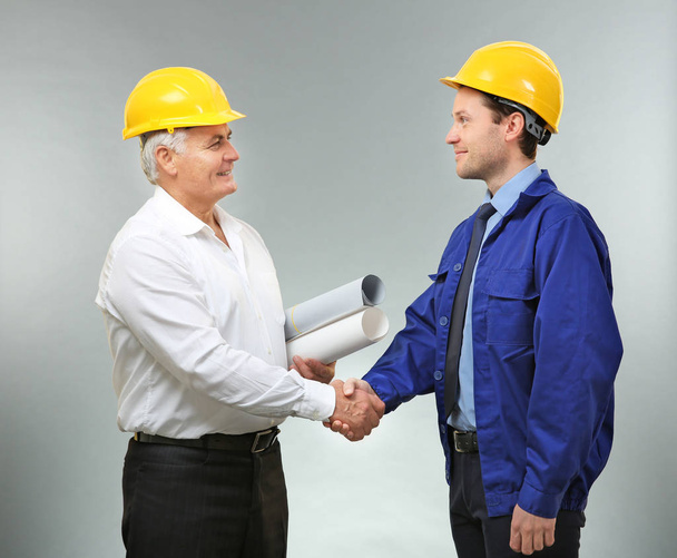 Senior engineer and worker shaking hands on light background - Photo, Image