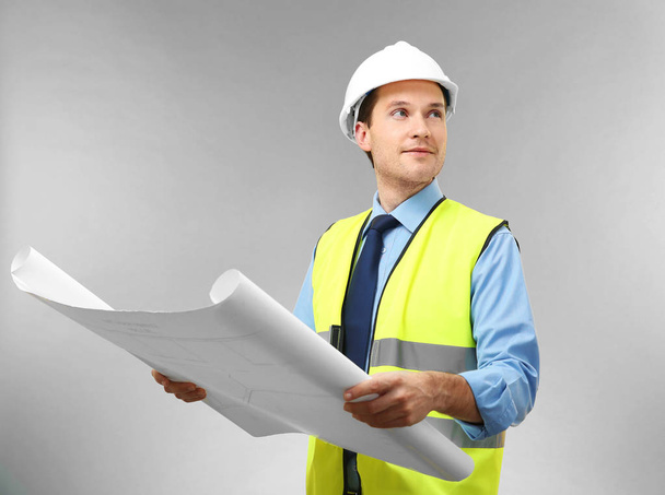 Handsome engineer with drawing on light background - Photo, Image