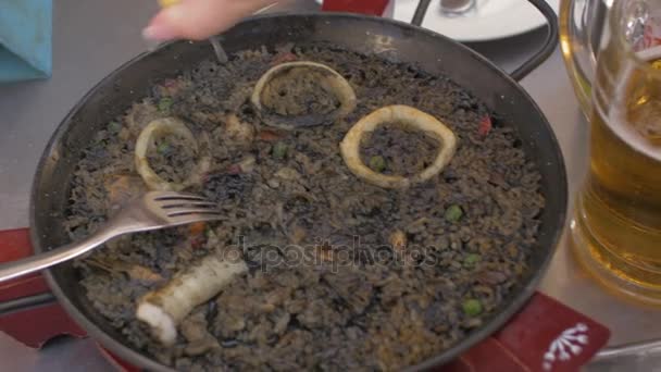 Woman eating black paella with seafood - Materiaali, video