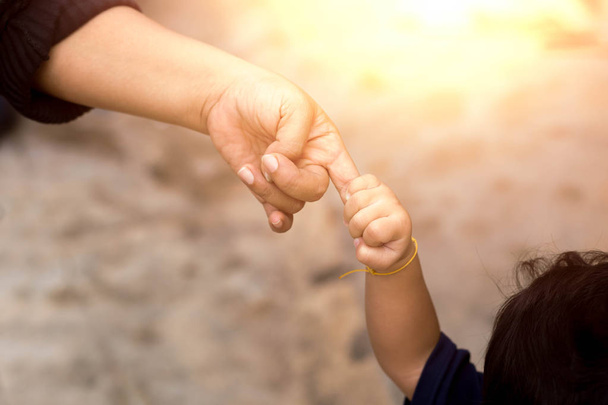 Kindje van haar moeder vinger tijdens het wandelen buiten bedrijf - Foto, afbeelding