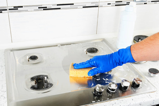 Cleaning a gas stove. Hand protection gloves when cleaning the kitchen. - 写真・画像