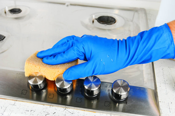 Reinigung eines Gasherdes. Handschutzhandschuhe beim Putzen der Küche. - Foto, Bild