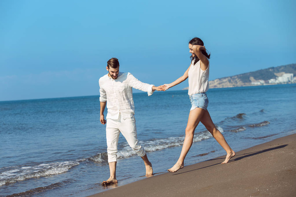 Young couple walking on beach smiling  - Foto, Imagem