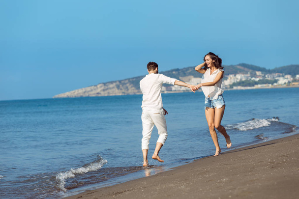 Young couple walking on beach smiling  - Zdjęcie, obraz