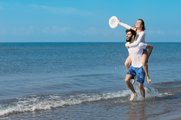 Een man met een meisje op rug op strand - Foto, afbeelding