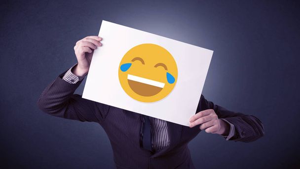 Empresário segurando papel com emoticon rindo
 - Foto, Imagem