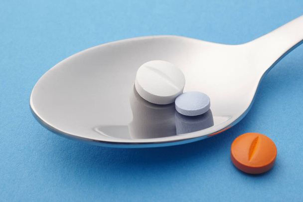 Χάπια και κουτάλι λεπτομέρεια. Μπλε φόντο. Φάρμακο θεραπεία. H - Φωτογραφία, εικόνα