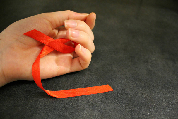 Red awareness ribbons in hand, isolated symbolic color logo concept lifting will campaign on health, public support for HIV STD cardiovascular disease - Photo, Image