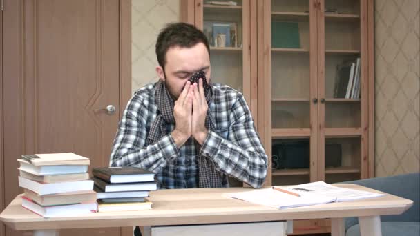 Sad and sick student getting down with flu sitting at the desk with books - Video, Çekim