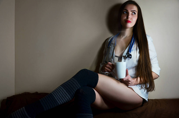 Young nurse girl sitting with coffee cup - Foto, Bild