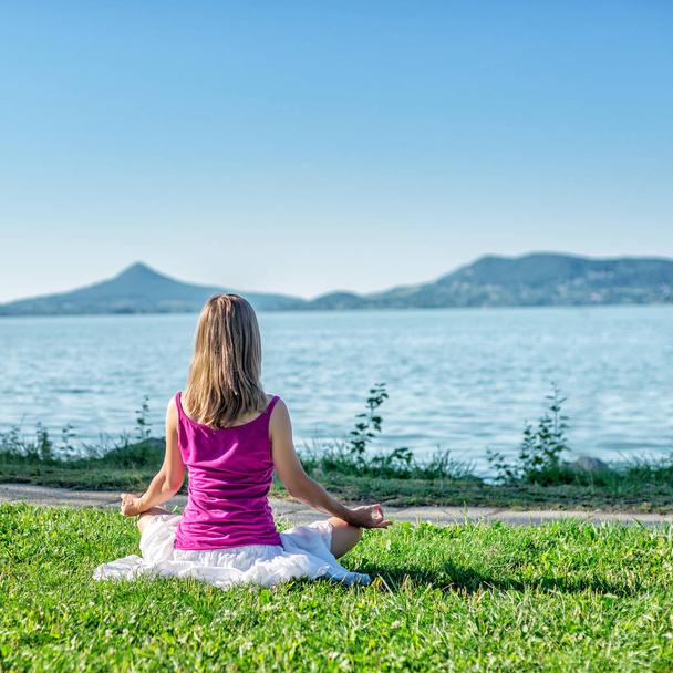 Женщина медитирует на озере
 - Фото, изображение