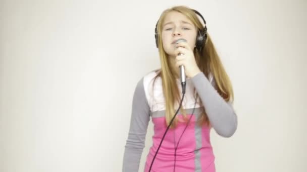 young girl listening music on headphones holding microphone, singing and funy dancing - Felvétel, videó