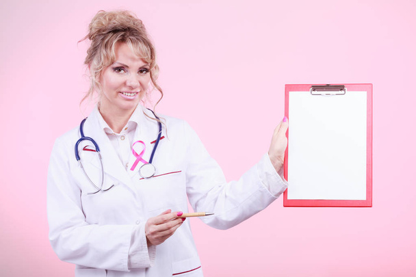 Doctor showing folder with pink ribbon by pen. - Фото, изображение