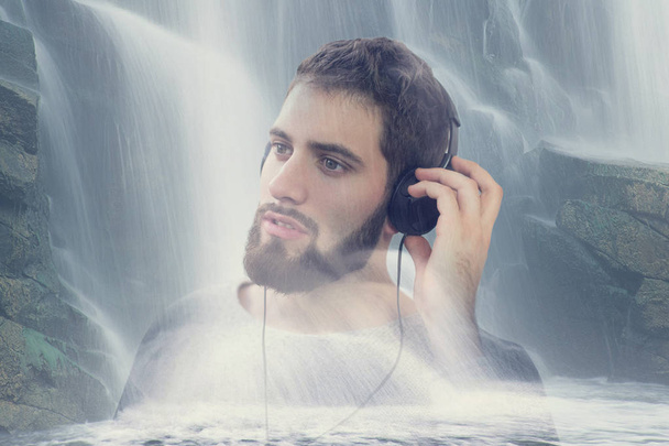 Ο άνθρωπος ακούει μουσική χαλάρωσης στη φύση με καταρράκτη διπλό exp - Φωτογραφία, εικόνα