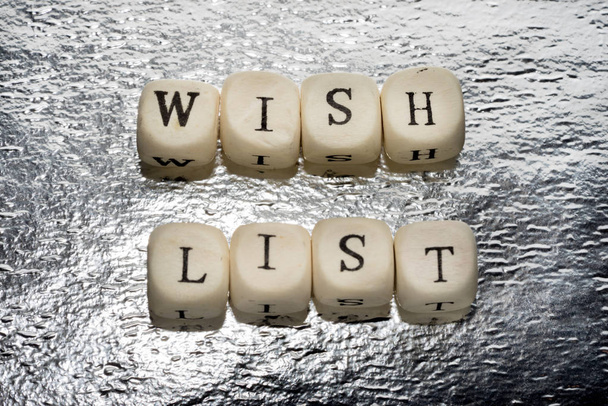 Wish list text on a wooden cubes on a shiny silver foil background - Photo, Image