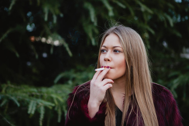 κορίτσι με μακριά μαλλιά καπνιστές στο πάρκο - Φωτογραφία, εικόνα