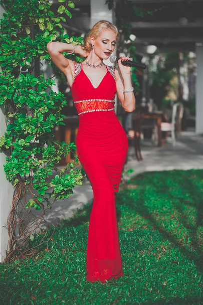Portrait of beautiful woman singer in red dress at restaurant  - Fotó, kép