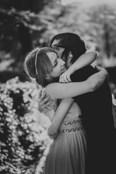 black and white photo of guy the girl embracing on a background park alley - 写真・画像
