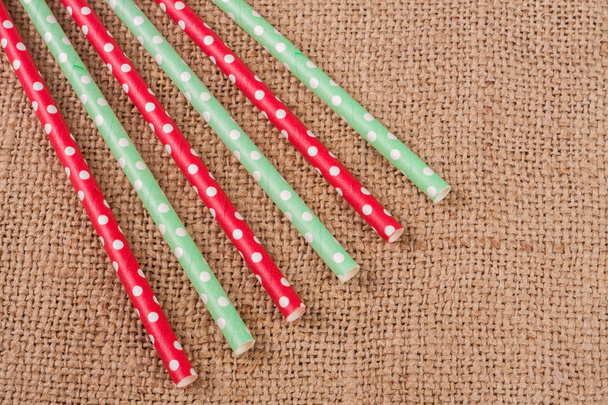 Colorful drinking striped straws on the background of burlap - Zdjęcie, obraz