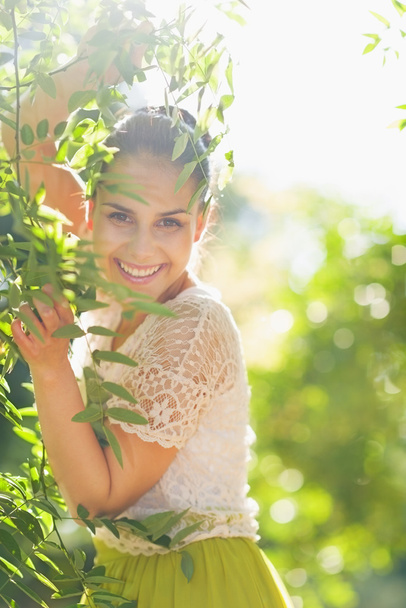 Smiling young woman playing in foliage - Фото, изображение
