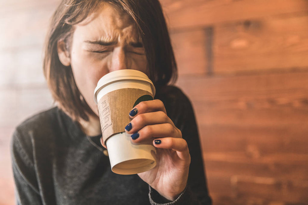 Young woman drinking a coffee and burning her tongue - Photo, Image