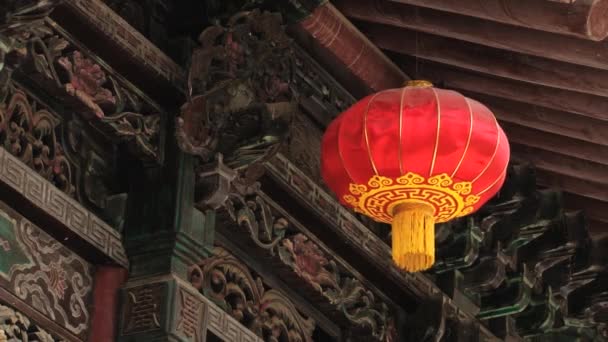 Traditional red Chinese lantern hangs with an aged carved and painted wooden building background in Xian, China.  - Footage, Video