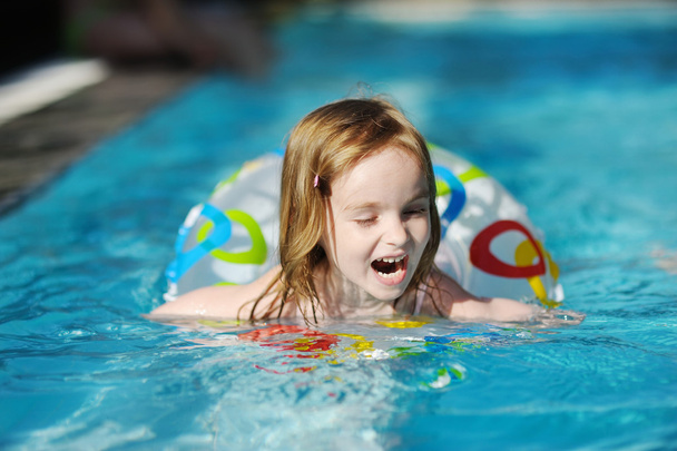 Pretty little girl swimming in a pool - Фото, зображення