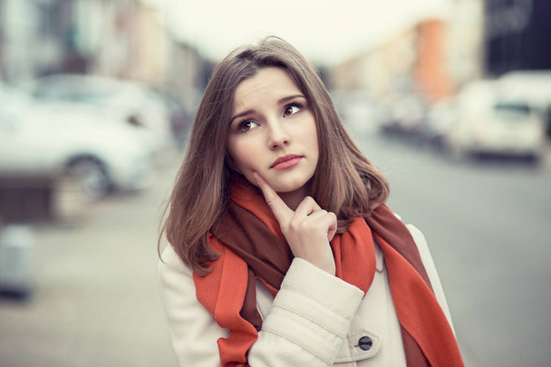 Woman thinking. Confident serious thoughtful young lady girl finger on cheek isolated cityscape outdoor background. - Foto, Imagen