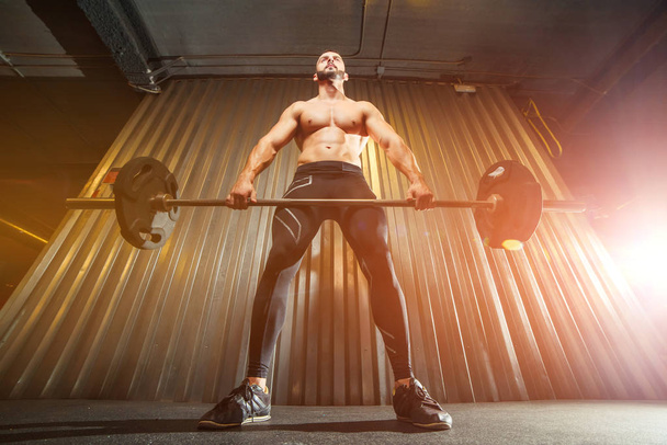 Muscular young man making deadlift with barbells at gym - Foto, imagen