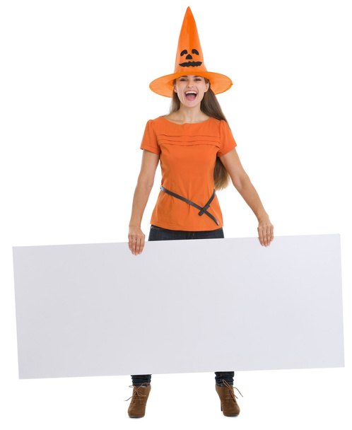 Smiling woman in Halloween hat holding blank billboard - Foto, imagen
