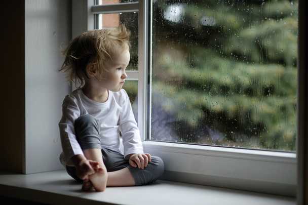 Adorable toddler girl looking at raindrops - 写真・画像