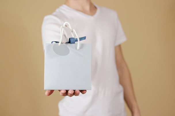 Man holding in hand blank blue paper gift bag mock up. Empty pac - Фото, зображення