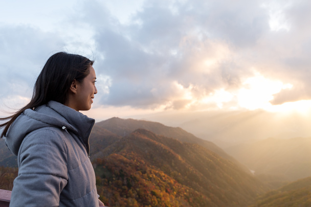 Жінка дивиться на захід сонця на горі
 - Фото, зображення