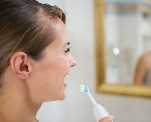 Happy woman brushing teeth with electric toothbrush - Foto, Imagen